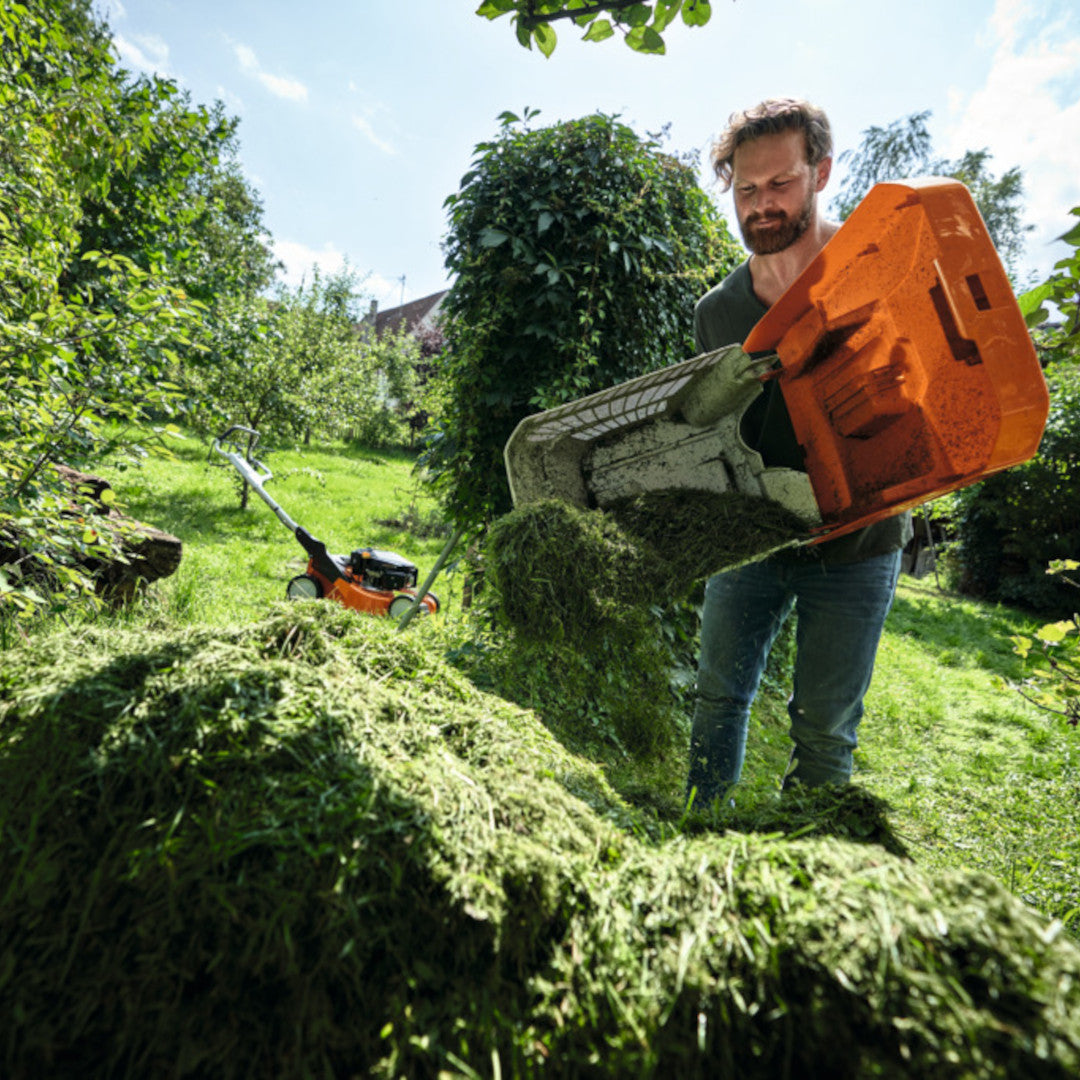 homme vidant un bac d'herbe tondeuse